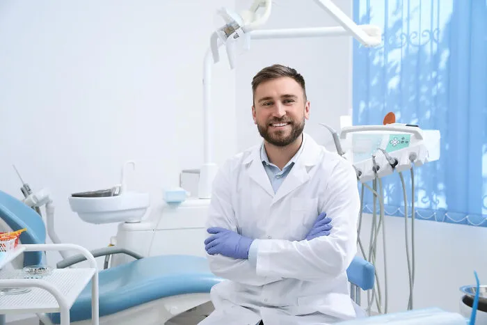 Smiling dentist in white coat ready for dental treatment
