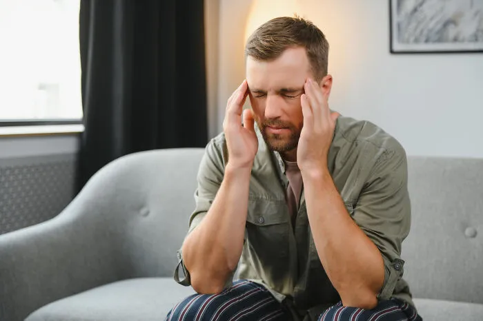 Man on a sofa holding his head, showing the emotional pain of seeing lifelong friendships fizzle out.