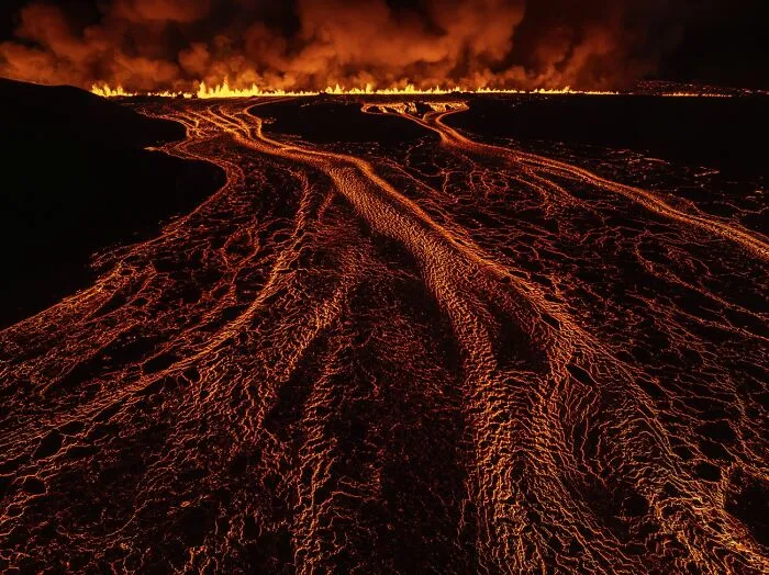Lava flows glowing brightly at night with fire line horizon volcanic photo