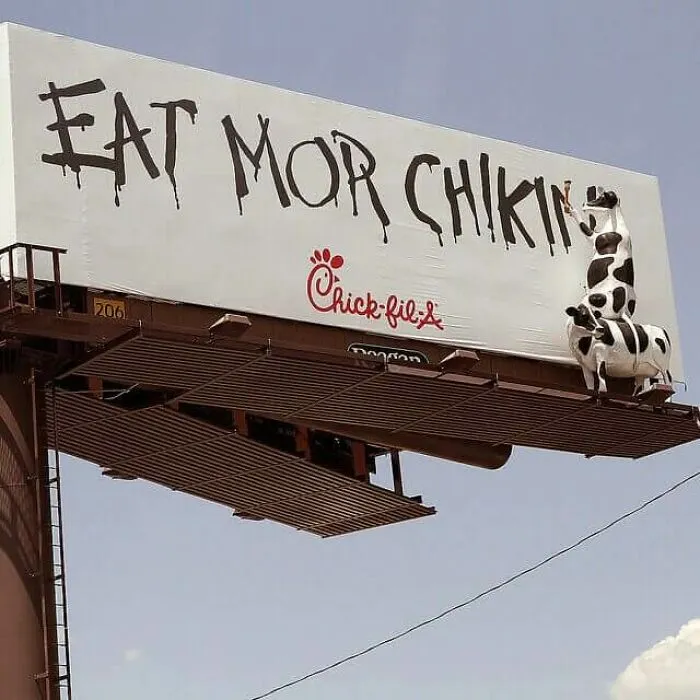 A Chick-fil-A billboard featuring cows painting text, an example of clever advertising fails.