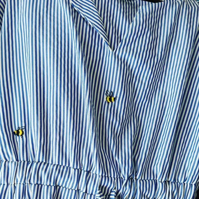 Tiny bumblebees embroidered on a blue striped top, showcasing how creativity can save money.