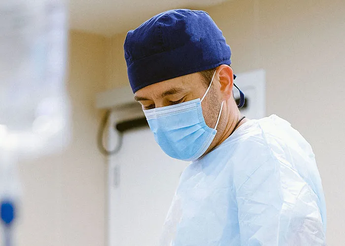 A doctor wearing a surgical mask and cap during a giving birth medical procedure.