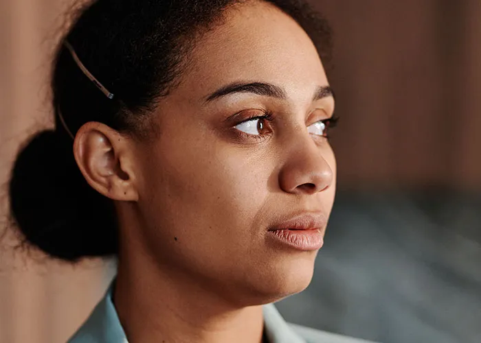 A woman looking thoughtful and concerned while reflecting on new motherhood