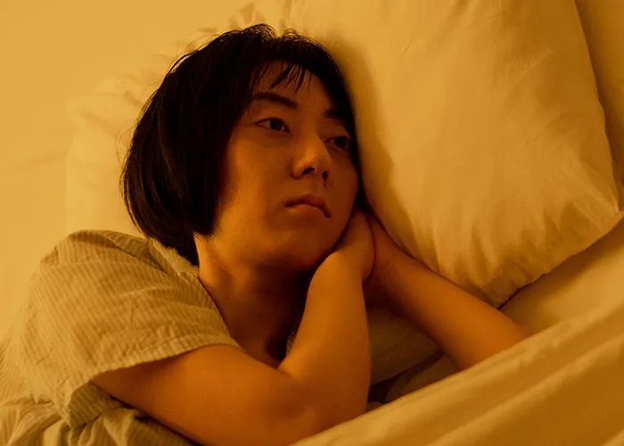Tired woman lying in bed resting, showing the physical exhaustion associated with post-giving birth recovery