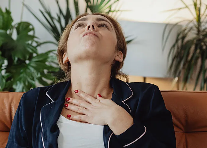 Exhausted woman touching her chest while resting, symbolizing the physical challenges after giving birth
