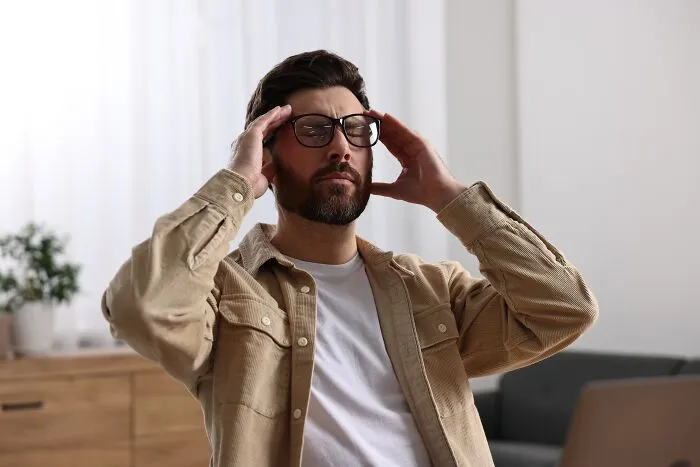 Frustrated man holding his temples in pain while feeling sick and stressed