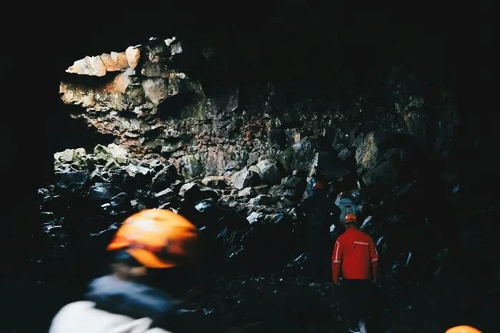 A group of explorers wearing safety helmets inside a dark cave, hinting at chilling scariest true stories.