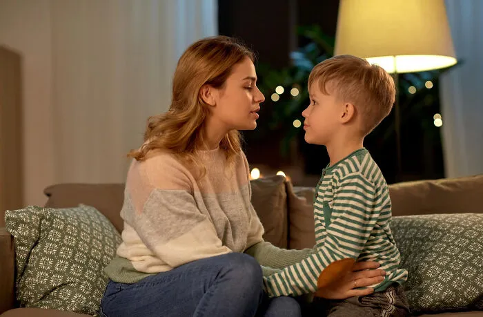 A mother talking softly to her young son on a couch as part of quick-fire jokes