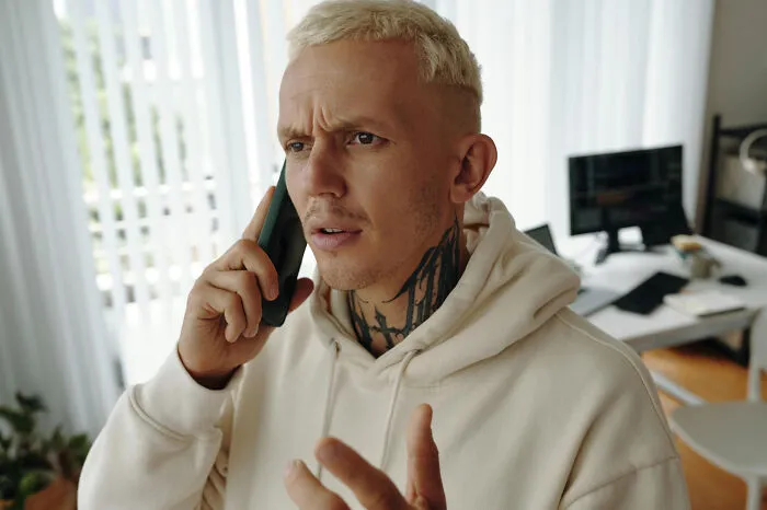 Tattooed man talking on phone with a confused look fitting quick-fire jokes