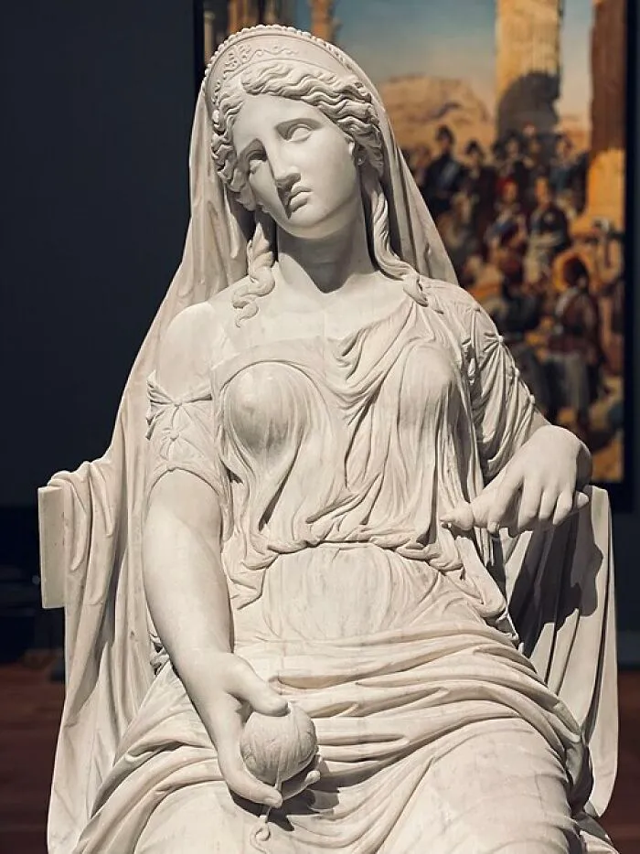 Classical white marble statue of a seated woman, representing timeless art and quick-fire jokes.