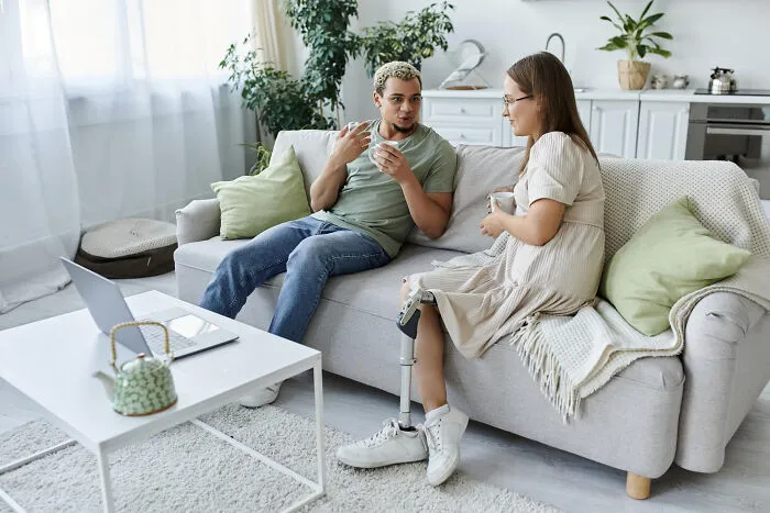 Couple sitting on a sofa chatting over coffee and telling quick-fire jokes.