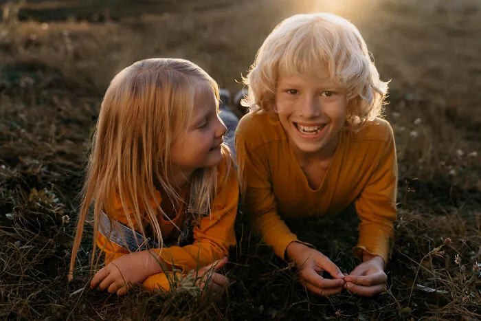 Two kids lying in the grass smiling and sharing quick-fire jokes.