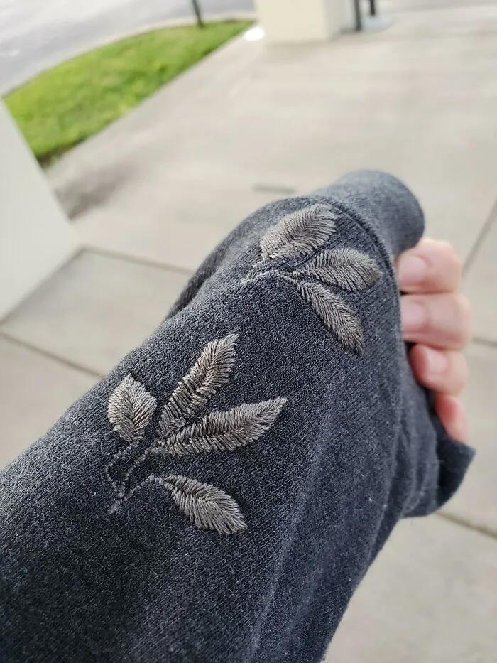 Delicate leaf embroidery repairing a grey sleeve, illustrating how creativity can save money.