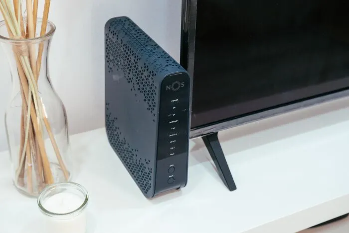 A black router sitting next to a television, representing unethical life pro tips for hacking wifi signals