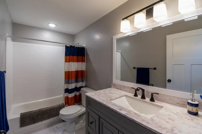 A modern bathroom with a vanity, toilet, and bathtub, showcasing unethical life pro tips for home staging.