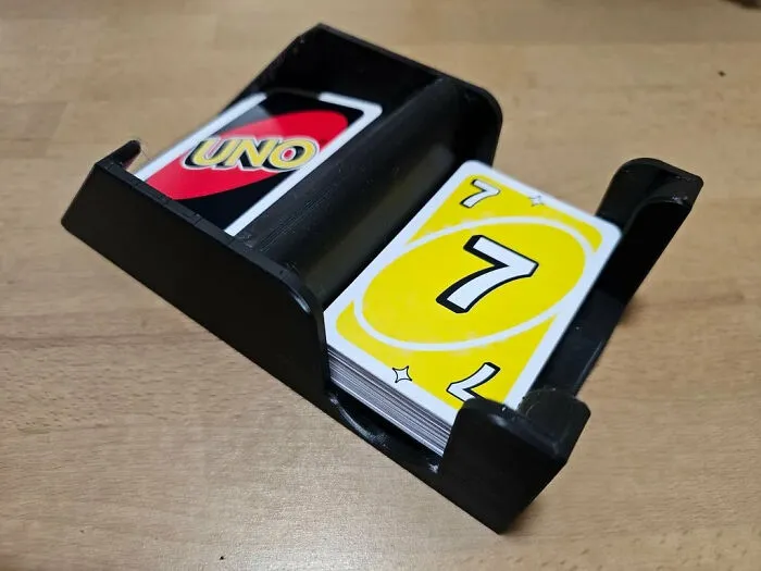 A black 3D printer card holder keeping Uno cards organized on a table.