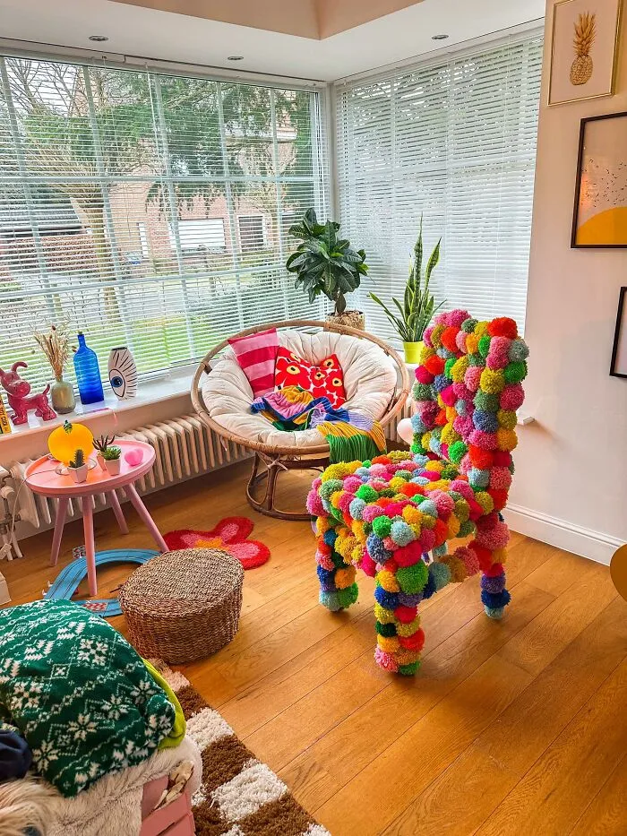 Colorful pom-pom accent chair in a brightly lit room after a home makeover.
