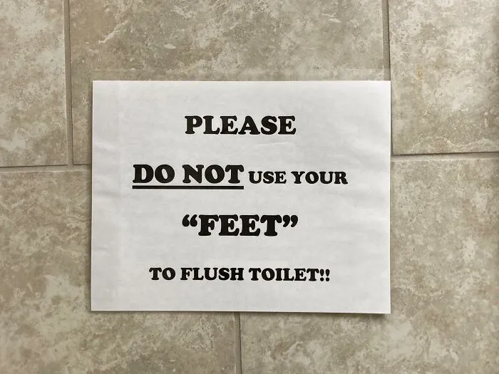 Paper sign on tiled wall showing misused quotation marks around the word feet in a bathroom instruction.