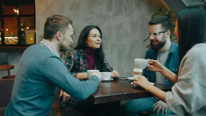 Four friends chatting and drinking coffee at a cafe, reflecting behaviors they refuse to tolerate.