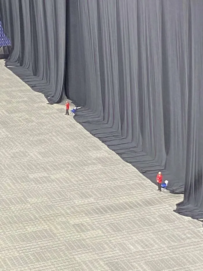 An interesting look at tiny security guards standing in front of massive black stage curtains