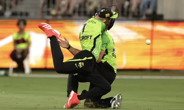 Two cricket players tumbling together creating a perfectly confusing photo perspective.