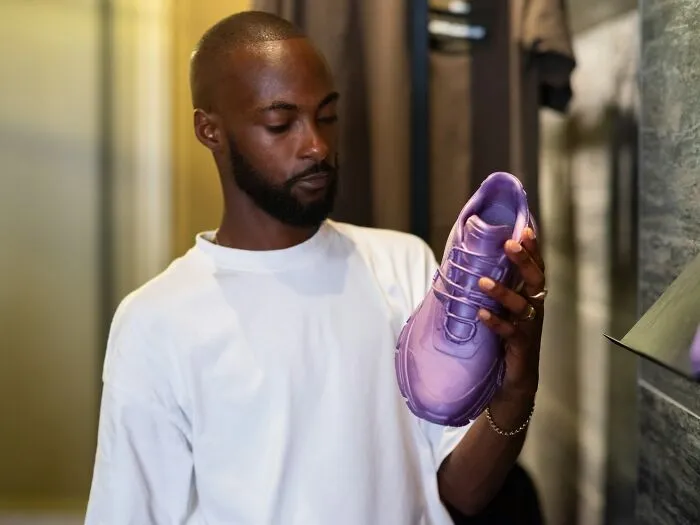 A man examining a stylish purple sneaker in a store setting, related to revenge stories