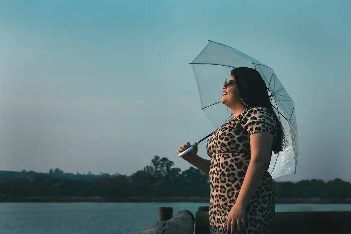 Confident plus-size woman with umbrella enjoying outdoor scenery