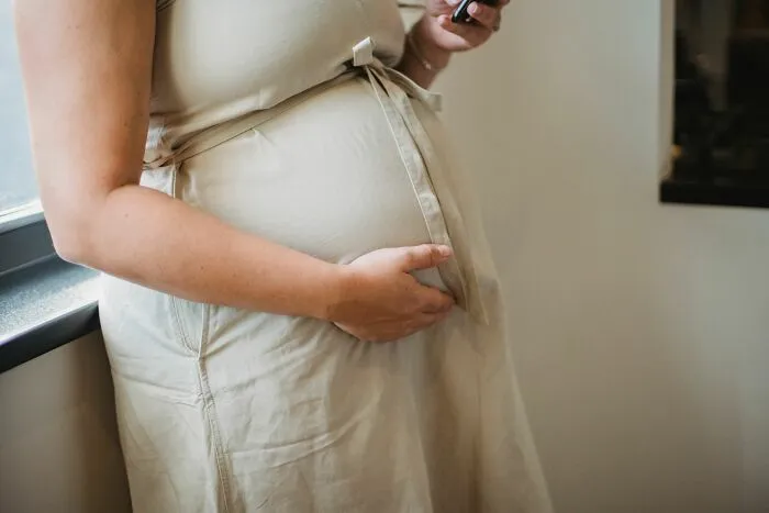 Pregnant woman holding belly highlighting weight-related comments