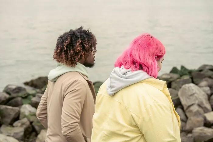 Two people with colorful hair standing near rocky shore
