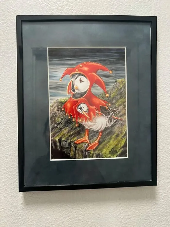 Framed artwork depicting a puffin dressed in a red jester hat, showcasing quirky thrift finds