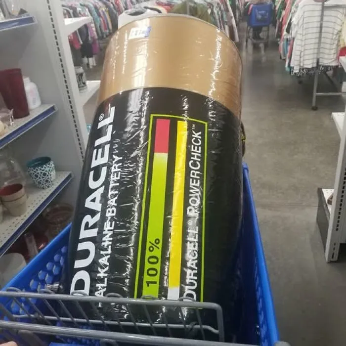 An oversized Duracell battery pillow inside a blue shopping cart, a rare thrift store treasure.
