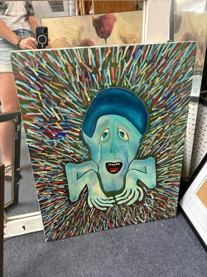 Handmade painting of a crying face on vibrant background, a unique thrift find.