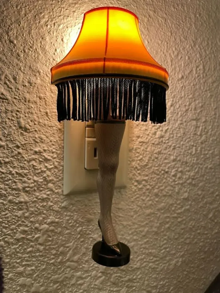Miniature Christmas Story leg lamp night light plugged into a wall outlet, a fun thrift find.