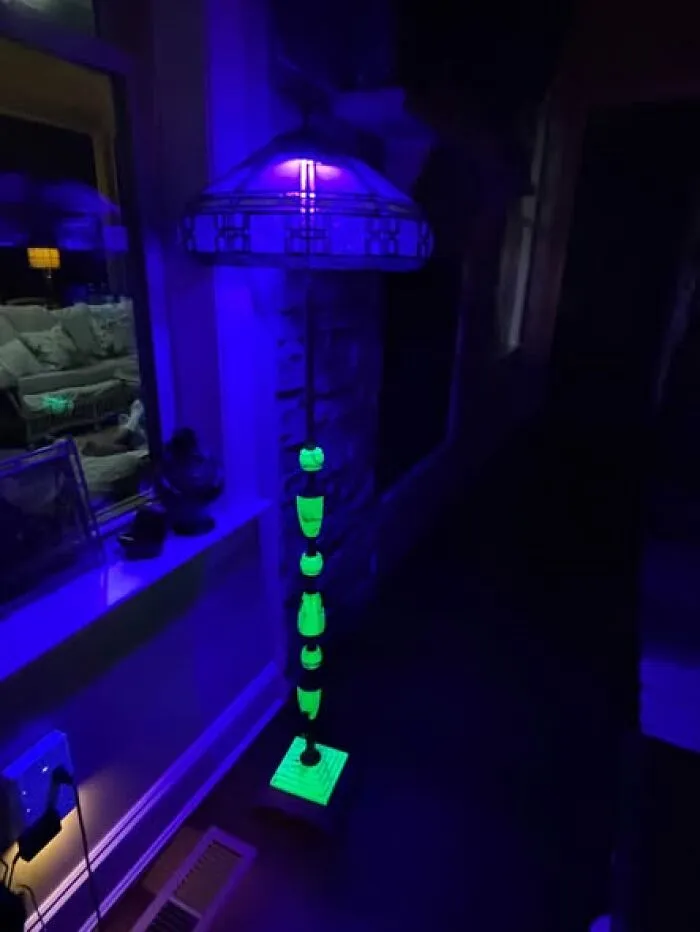 Unique uranium glass floor lamp glowing bright green under UV light, one of many cool thrift finds.