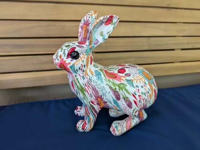 Floral patterned bunny figurine sitting on a blue surface, representing a unique thrift find.