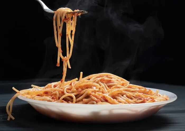 A fork lifting steaming hot spaghetti, illustrating human body facts related to taste and digestion.