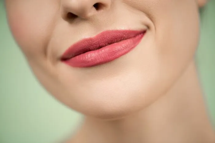 Close-up of a person smiling with pink lipstick showing human body facts about skin and lips.