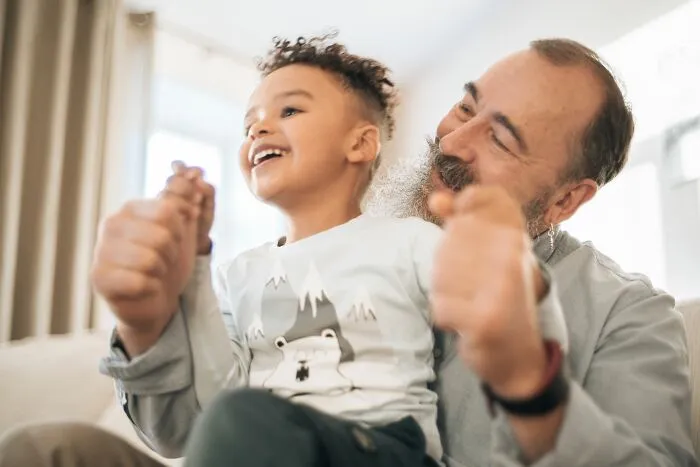 A happy young child playing with a smiling older man, illustrating interesting human body facts.