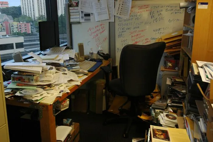 Extremely messy office desk piled with papers and clutter, typical of weird at work habits