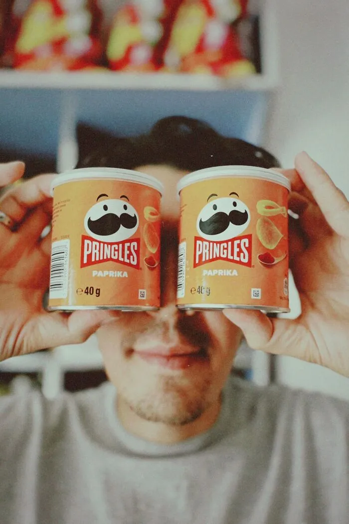 A person holding two chip cans over their eyes, acting weird at work.
