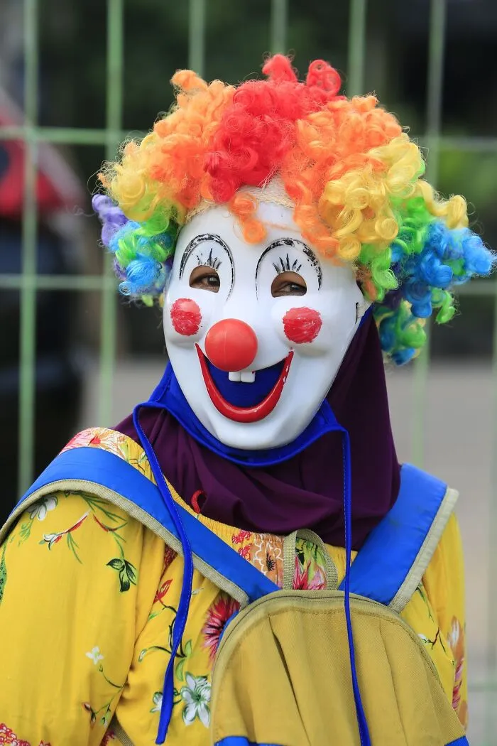A person wearing a clown mask and rainbow wig representing weird at work moments.