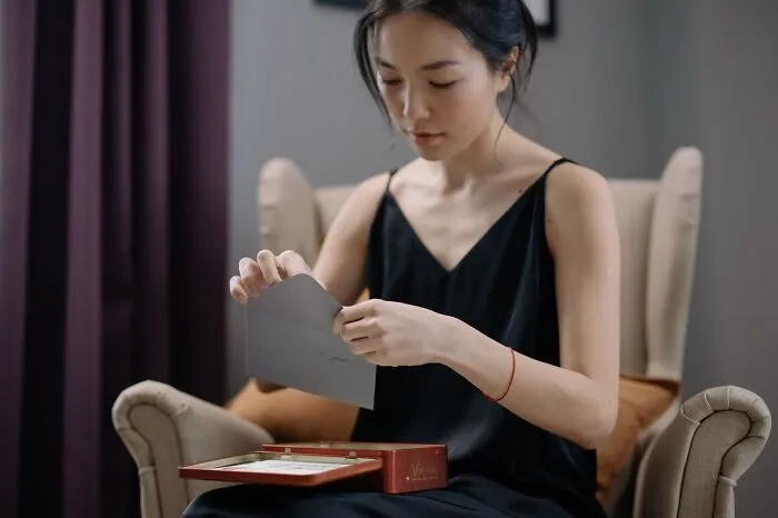 A woman opens a letter while seated, reflecting weird at work behavior.