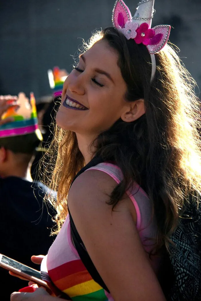A smiling woman wearing a pink unicorn headband, illustrating weird at work personalities.