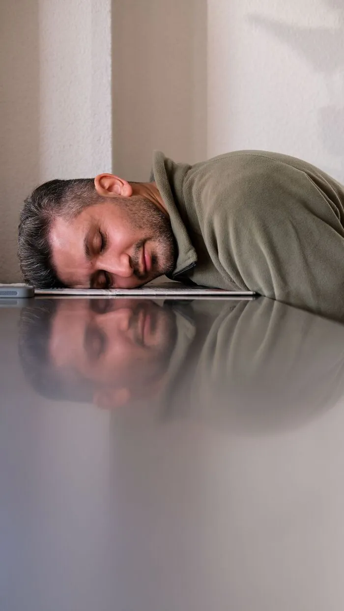 A man sleeping on his table at work with his head resting on paper