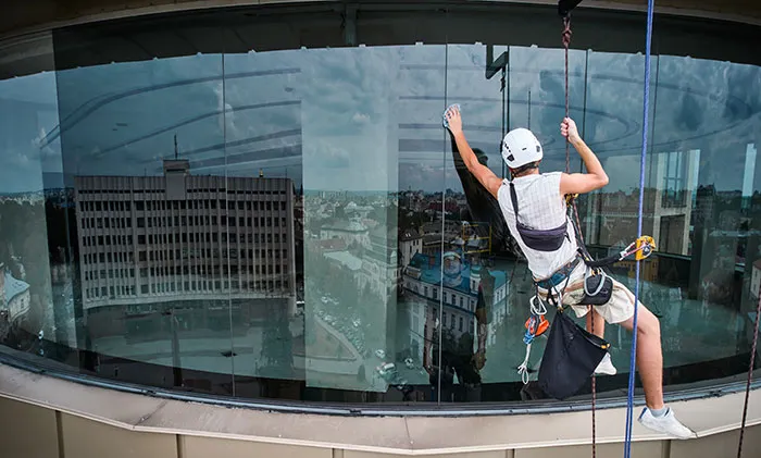 Window cleaner suspended by rope performing dangerous building cleaning job
