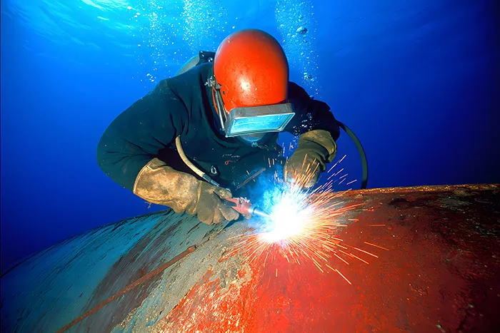 Underwater welder performing welding task on submerged metal structure