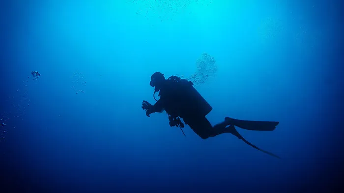 Silhouette of diver underwater highlighting risky and well-paying commercial diving jobs