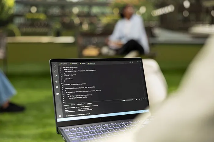 Programmer coding on laptop outdoors in a high paying tech job