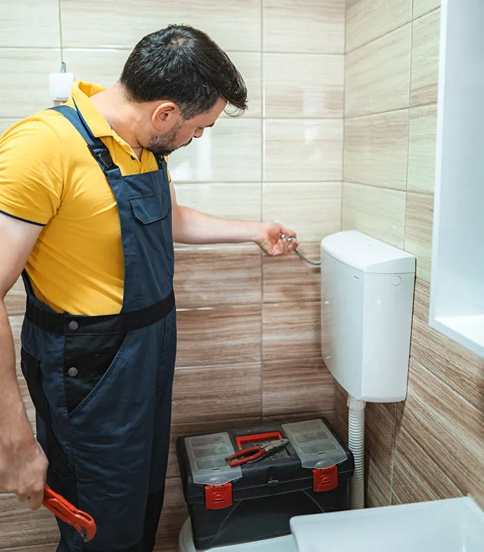Plumber fixing toilet cistern in a small bathroom space