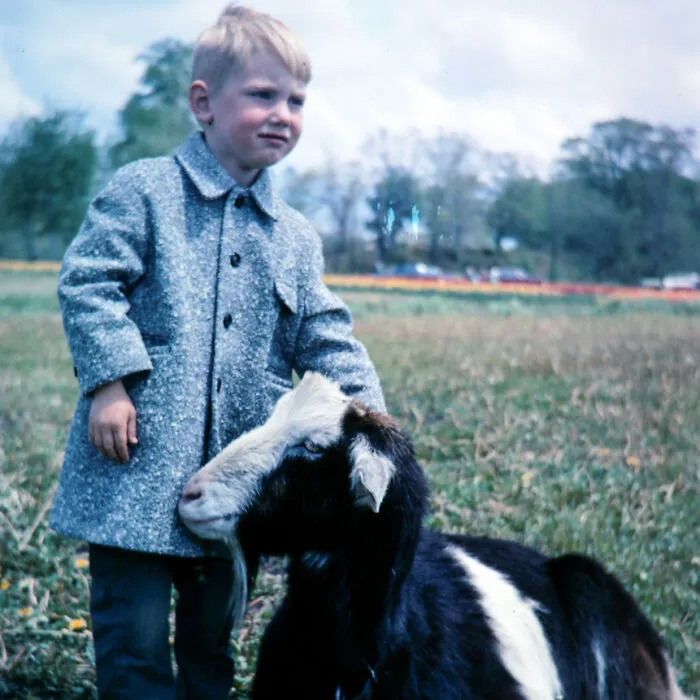 Young boy standing next to a goat outdoors in a sweet wholesome moment shared on the internet.